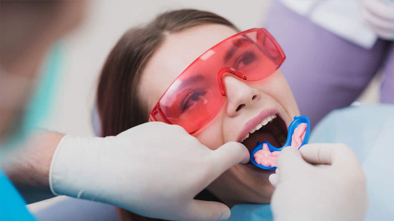 Woman getting fluoride treatment at dental office