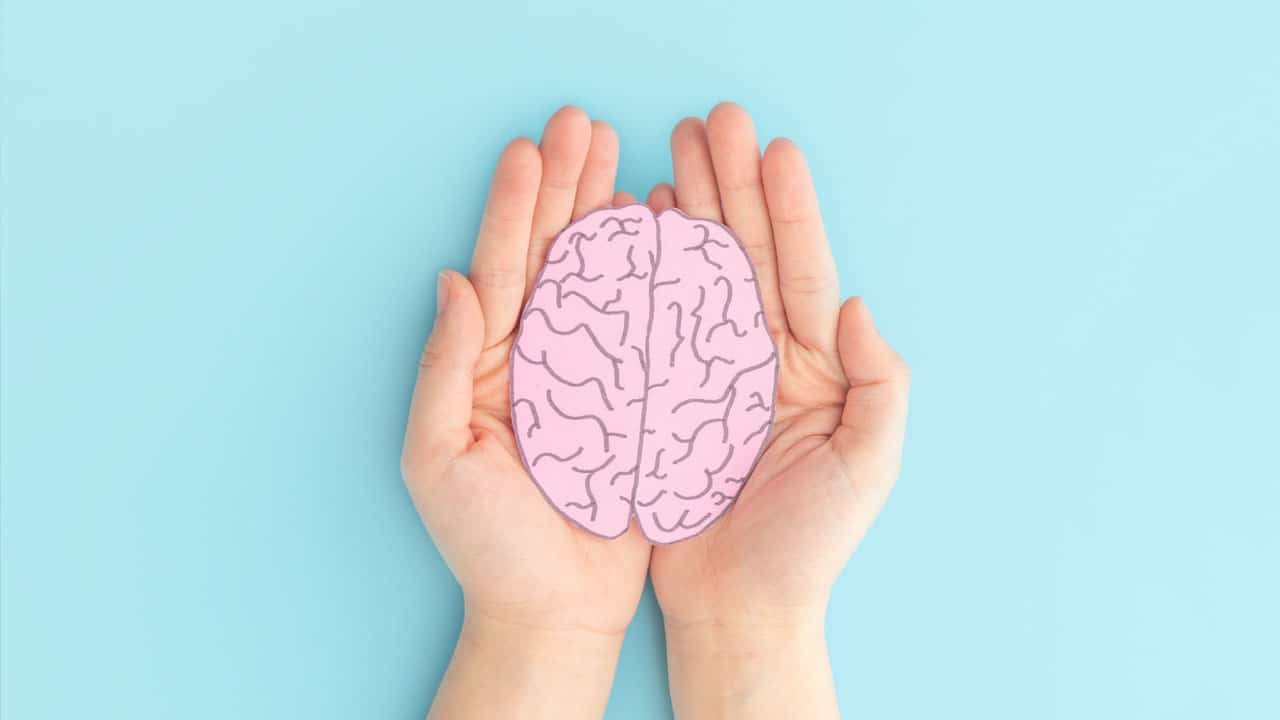 Woman hands holding human brain shape made from paper on light blue background