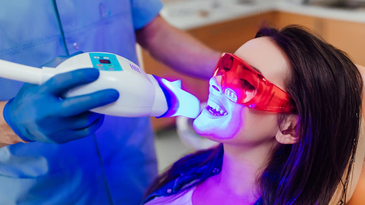 Woman at dental office whitening teeth